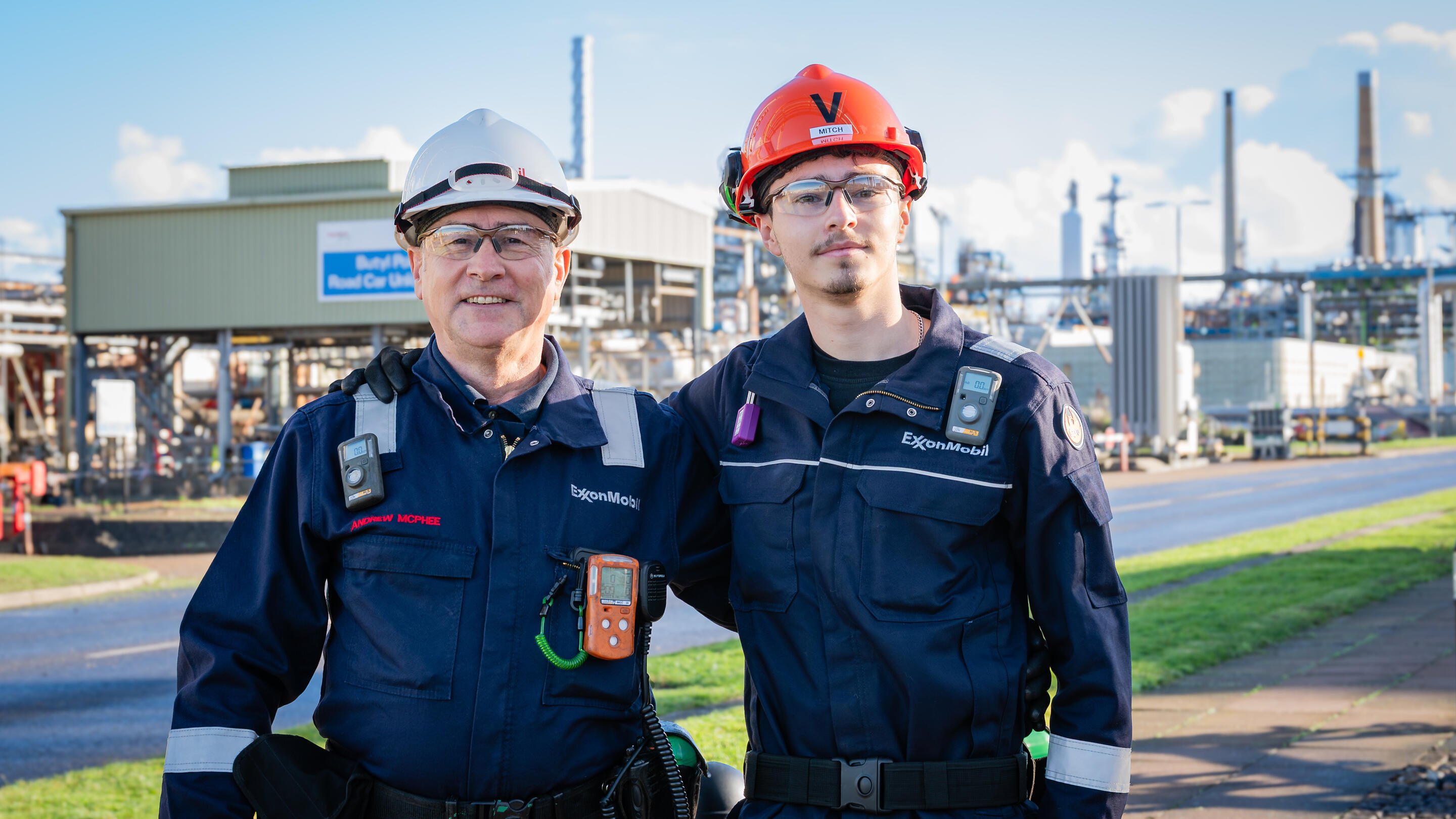 ExxonMobil Fawley (United Kingdom) employees Andrew and Mitchell Mcphee wearing protective gear and standing in front of complex