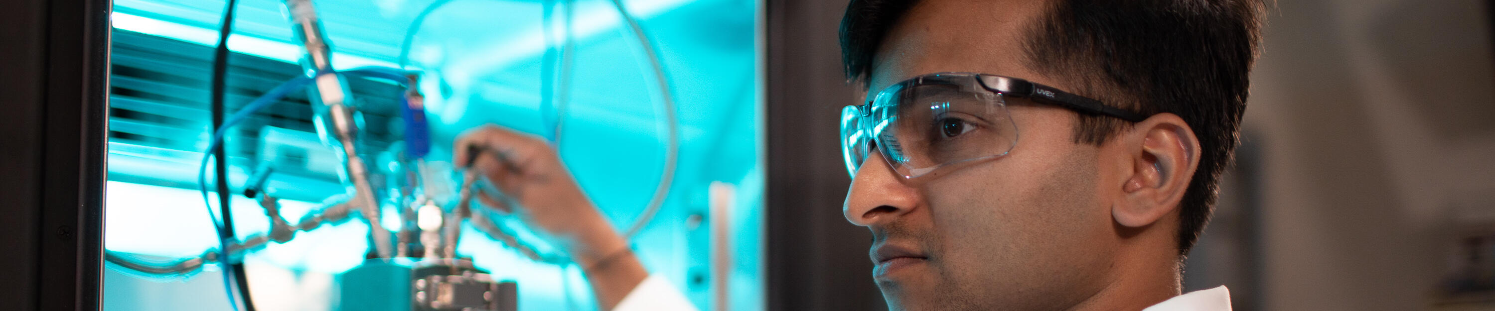 ExxonMobil UT at Austin fellowship program participant working in lab, wearing safety eyewear and lab coat