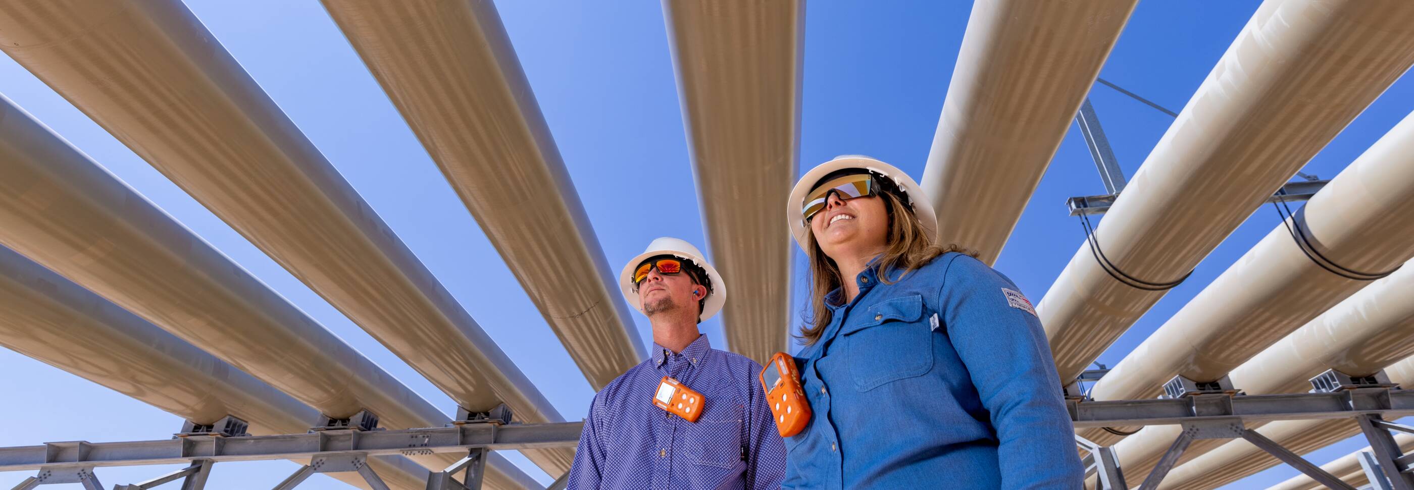 Workers standing under pipes.