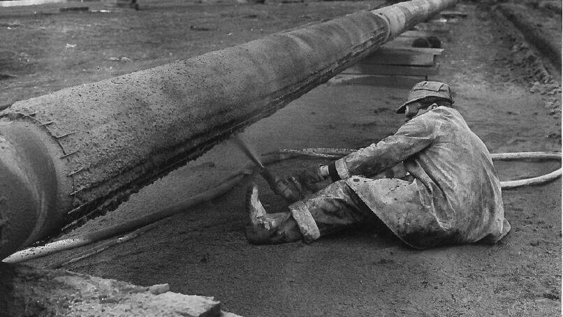 Image 1963 - A workman applies a concrete coating to one of the pipes from Fawley to London to protect them from any damage which may occur on the river bed.